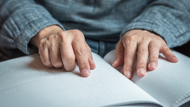 older hands tracing words on a page while reading